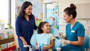 Happy Hispanic child with a parent and pediatric dentist during a dental visit at Happy Kids Pediatric Dentistry.
